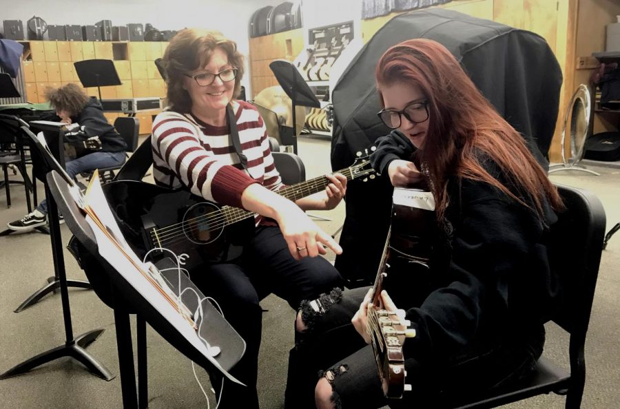 Community member Janet Belding assists sophomore Lauren Ingram in correct finger placement for a guitar note.
